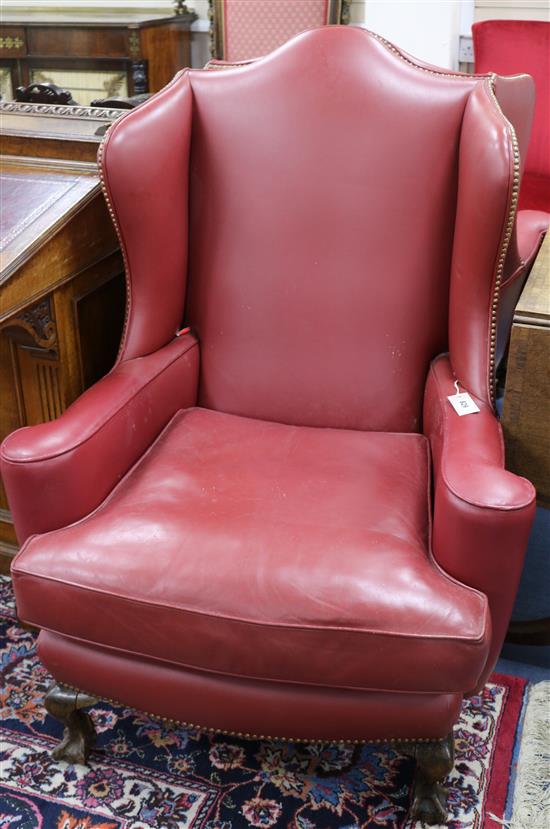 A pair of 1920s burgundy leather wing armchairs, on ball and claw feet